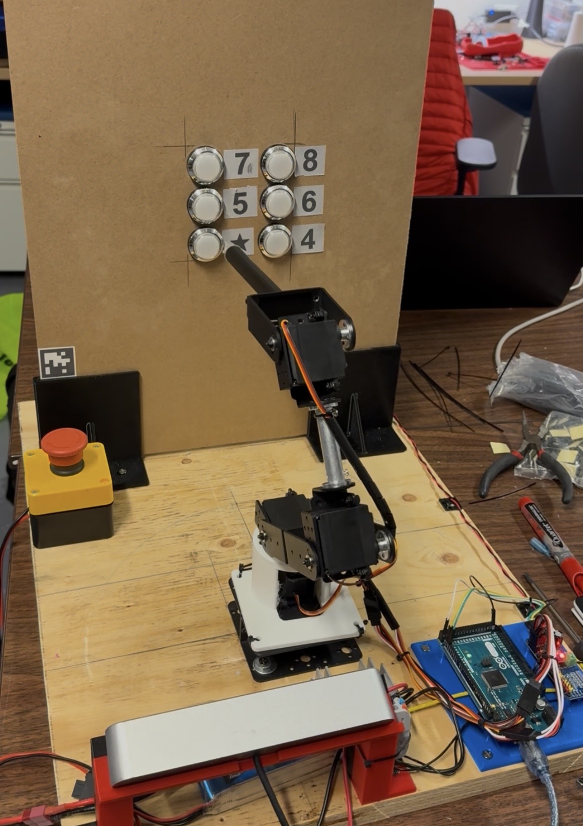 Assistive robotic arm prototype operating a mock elevator panel